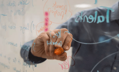 Endeavor selects 102 scale-ups for acceleration program. Image shows a person writing on a transparent board with a colored pen.
